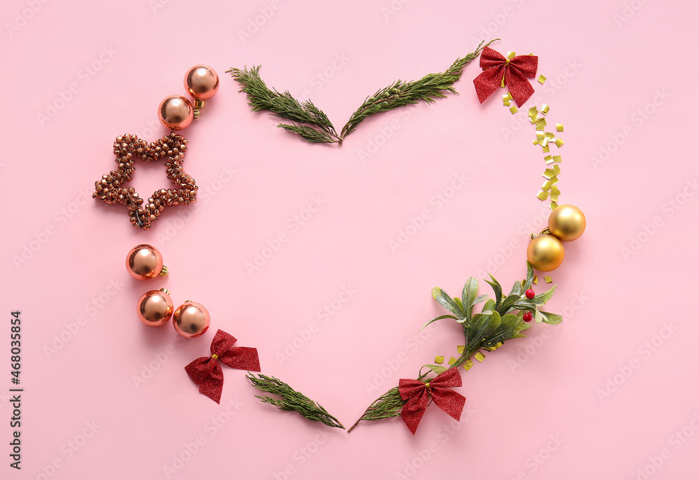 Heart made of coniferous branches and Christmas decor on pink background