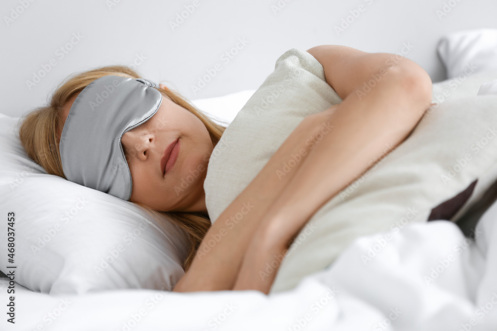 Mature woman with mask sleeping in bed