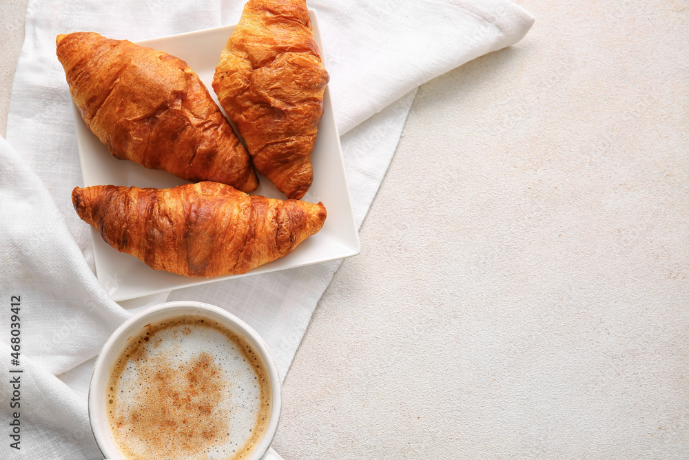 Plate with delicious croissants and cup of coffee on white background