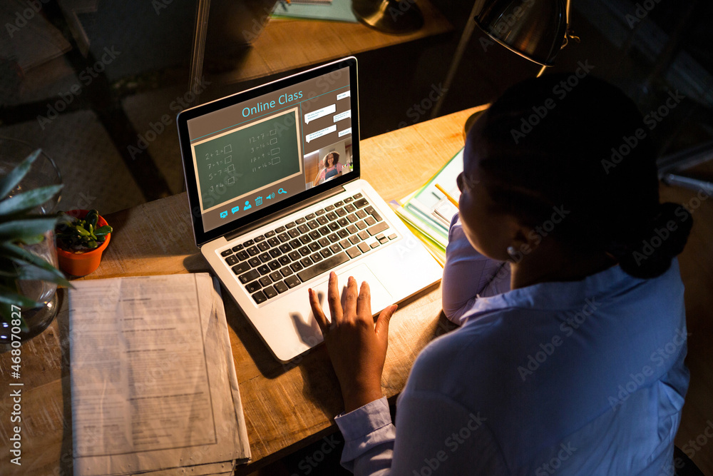 African american woman using laptop for video call, with smiling female teacher on screen