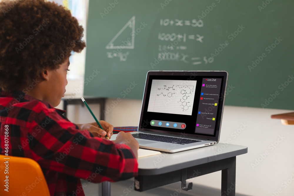 African american boy using laptop for video call, with class on screen