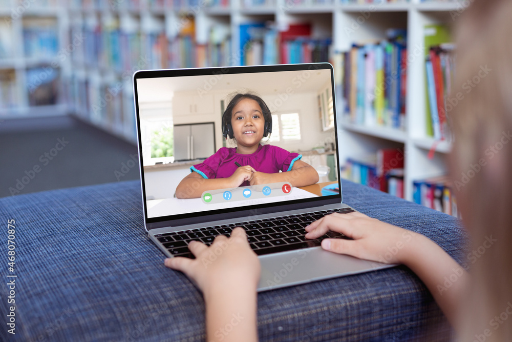 Caucasian girl using laptop for video call, with smiling elementary school pupil on screen