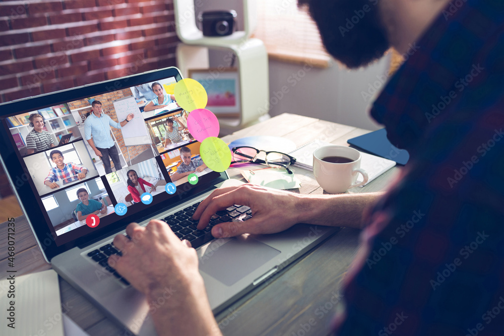 Caucasian man using laptop for video call, with smiling diverse elementary school pupils on screen