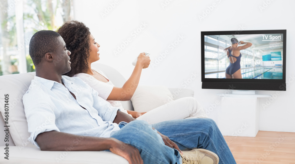 Rear view of african american couple sitting at home together watching swimming competition on tv