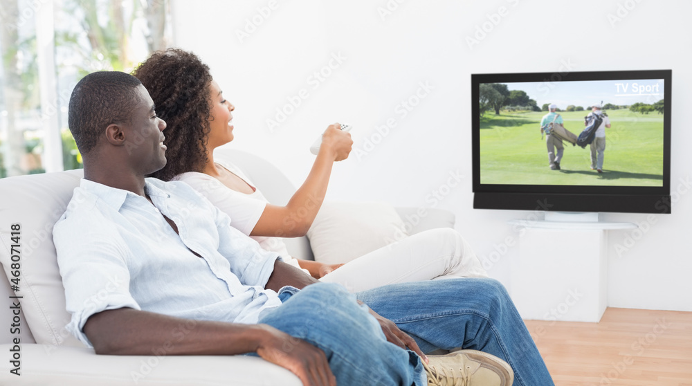 Rear view of african american couple sitting at home together watching golf on tv