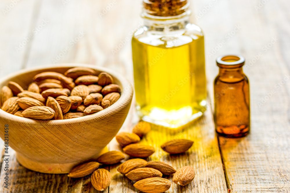 cosmetic and therapeutic almond oil on light wooden background