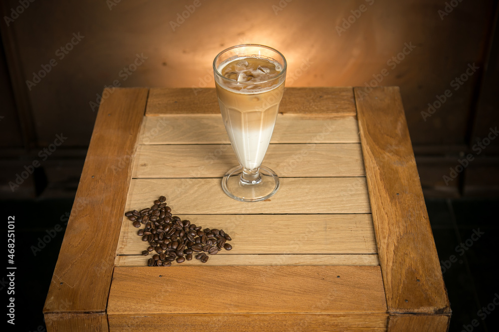 glass of cappucino and coffee beans on woden case