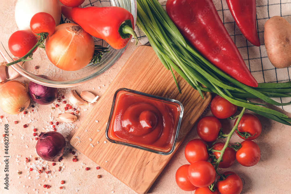 Bowl with organic tomato sauce and ingredients on color background