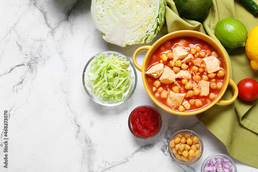 Composition with delicious pozole soup in pot and ingredients on light background