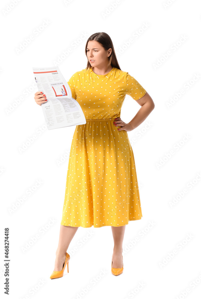 Upset young woman in yellow dress reading newspaper on white background