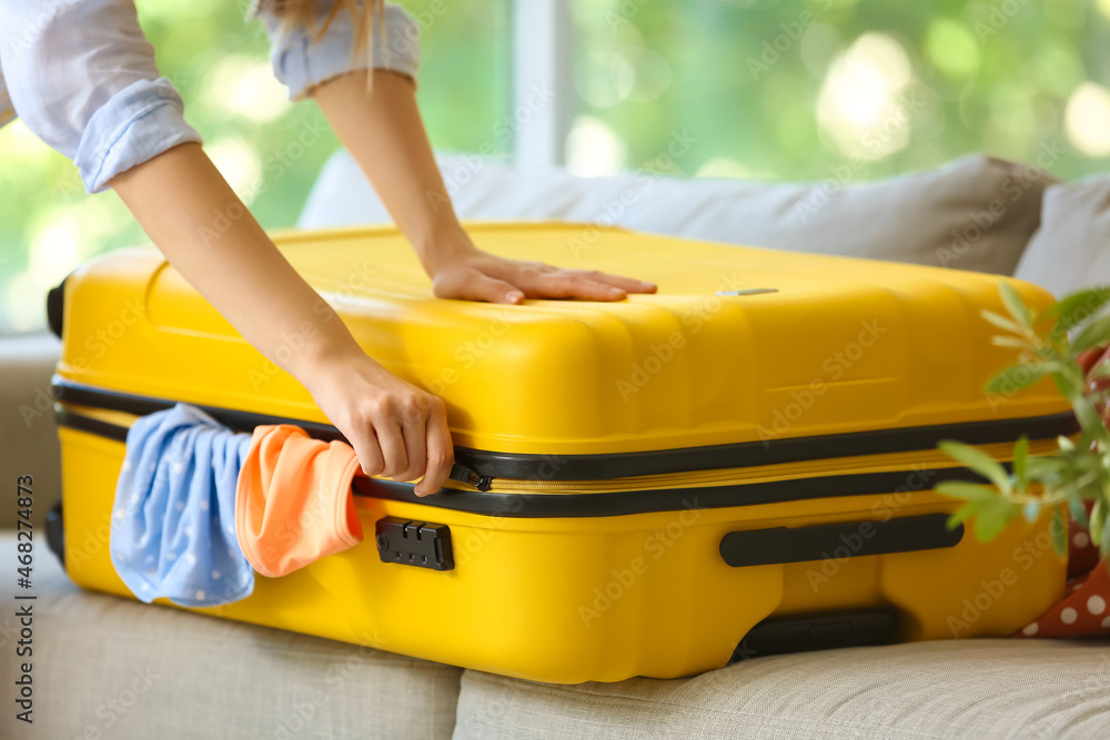 Female tourist trying to close suitcase with a lot of things