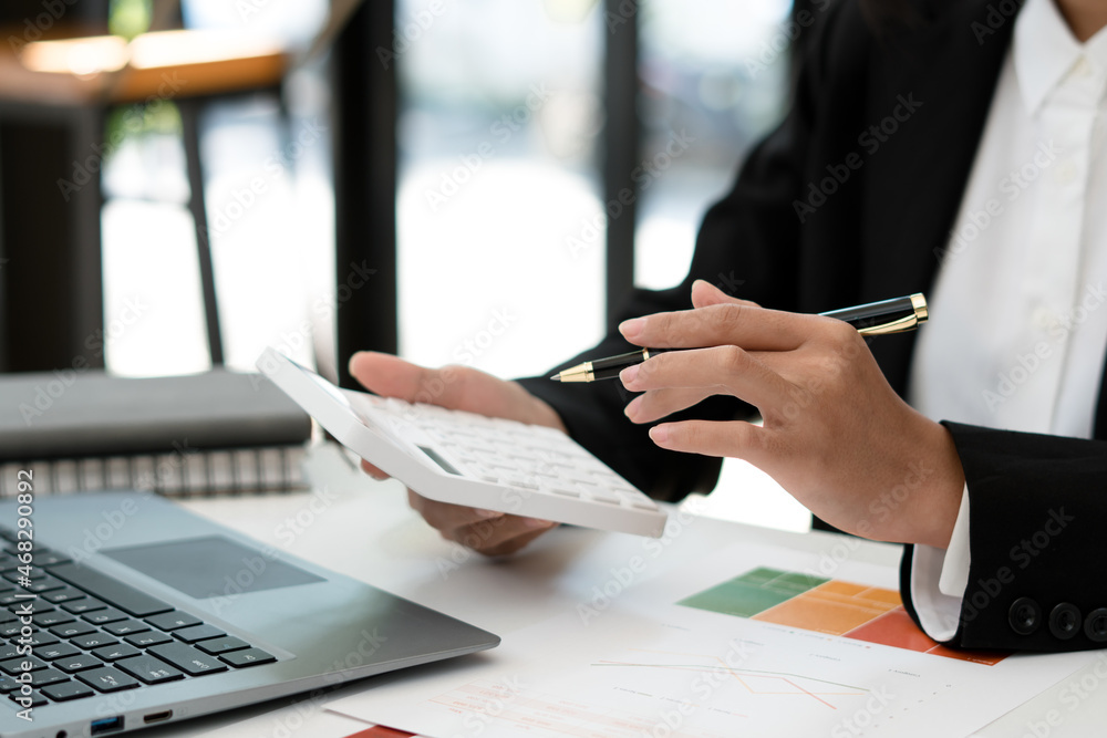 Close up hand of businessman or accountant hand holding pen working on calculator to calculate busin