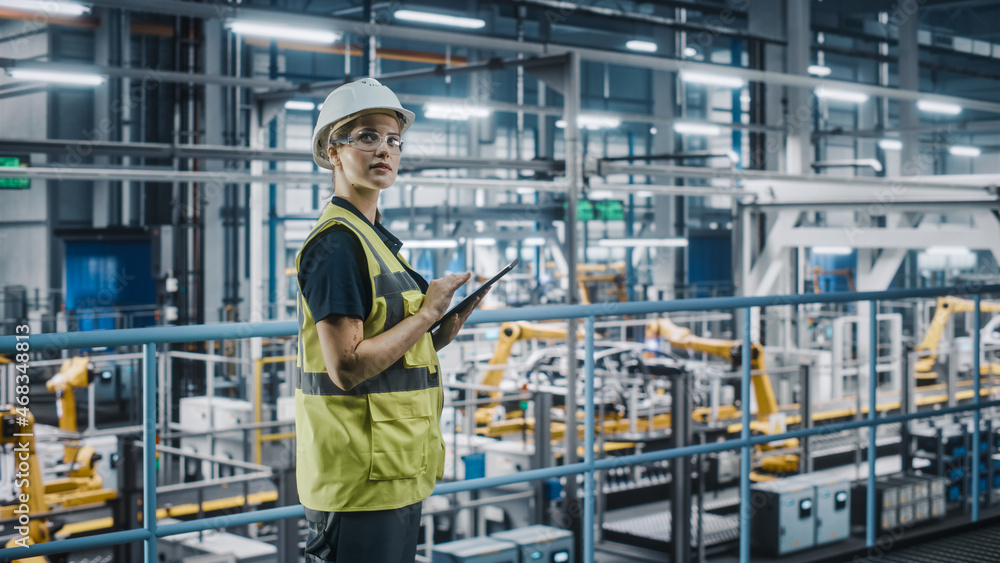 Female Car Factory Engineer in High Visibility Vest Using Laptop Computer. Automotive Industrial Man