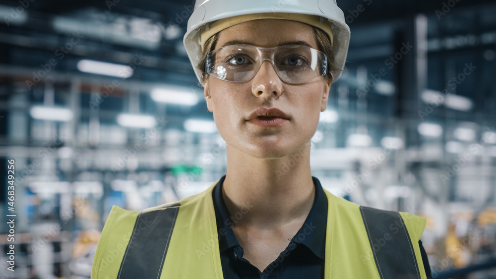 Portrait of Female Automotive Industry Engineer Putting on Safety Glasses at Car Factory Facility. C