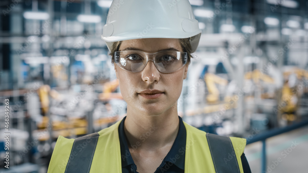 Portrait of Female Automotive Industry Engineer Putting on Safety Glasses at Car Factory Facility. C