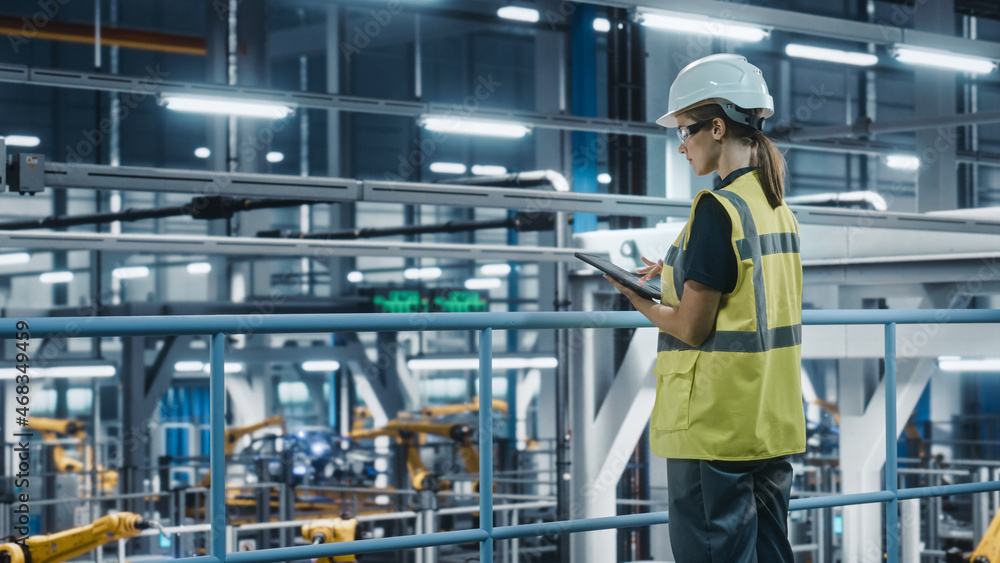 Female Car Factory Engineer in High Visibility Vest Using Tablet Computer. Automotive Industrial Man