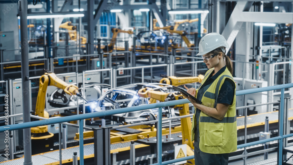 Female Car Factory Engineer in High Visibility Vest Using Tablet Computer. Automotive Industrial Man