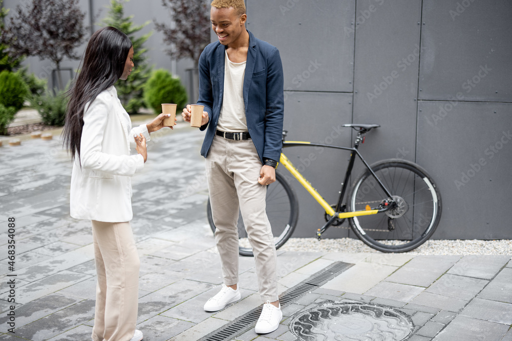 Businessman and businesswoman talking and drinking coffee outdoors. Concept of break on job. Idea of