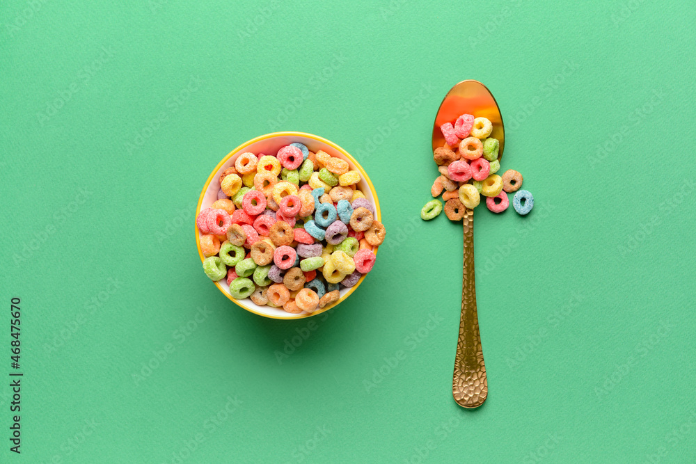 Bowl and spoon with crunchy corn flakes rings on color background