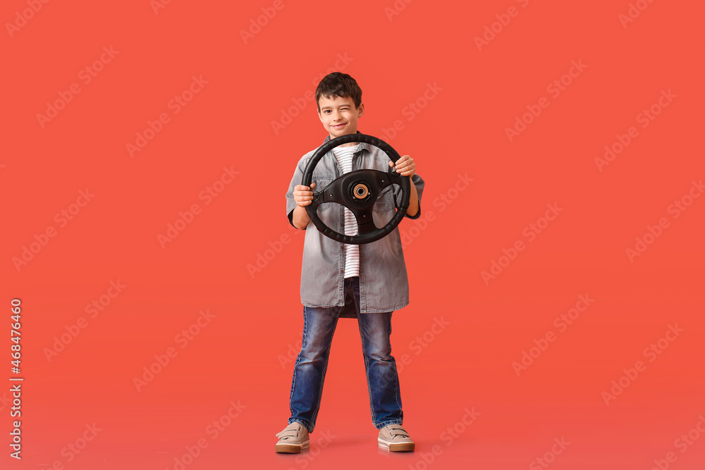 Cute little boy with steering wheel on color background