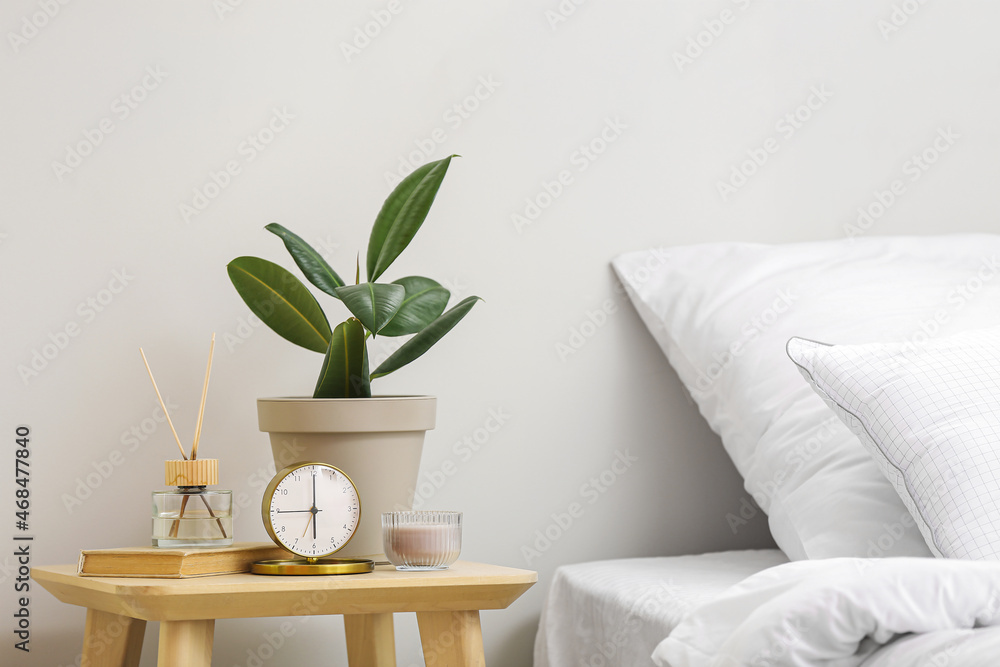 Interior of stylish bedroom room with alarm clock and houseplant on table