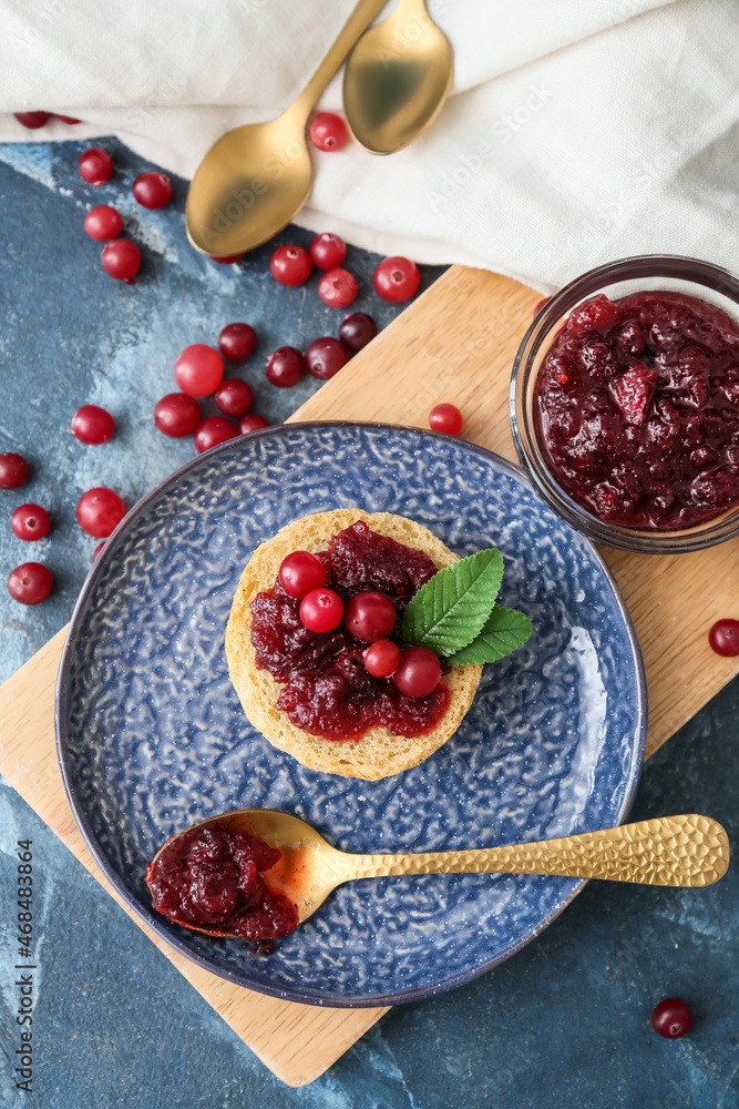 Tasty sandwich with cranberry jam and fresh berries on blue background