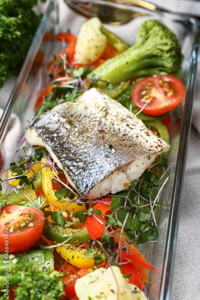 Baking dish of delicious sea bass fish with vegetables on table, closeup