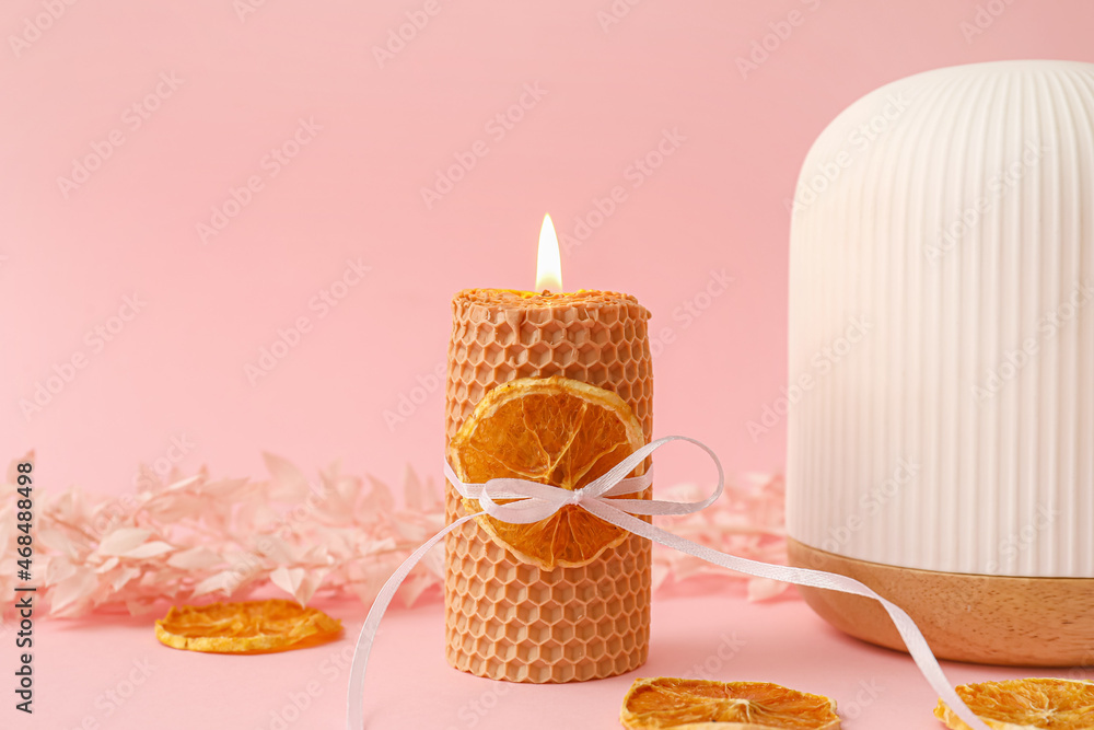 Burning candle, plant branch, slices of dry orange and aroma diffuser on color background