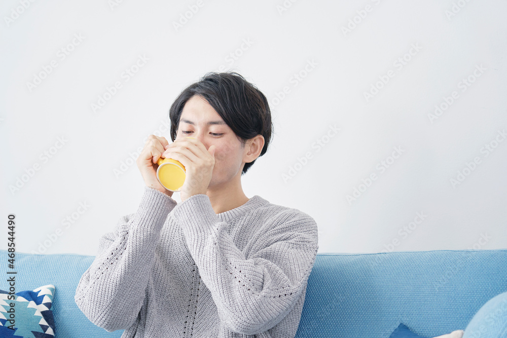 マグカップで飲み物を飲む男性