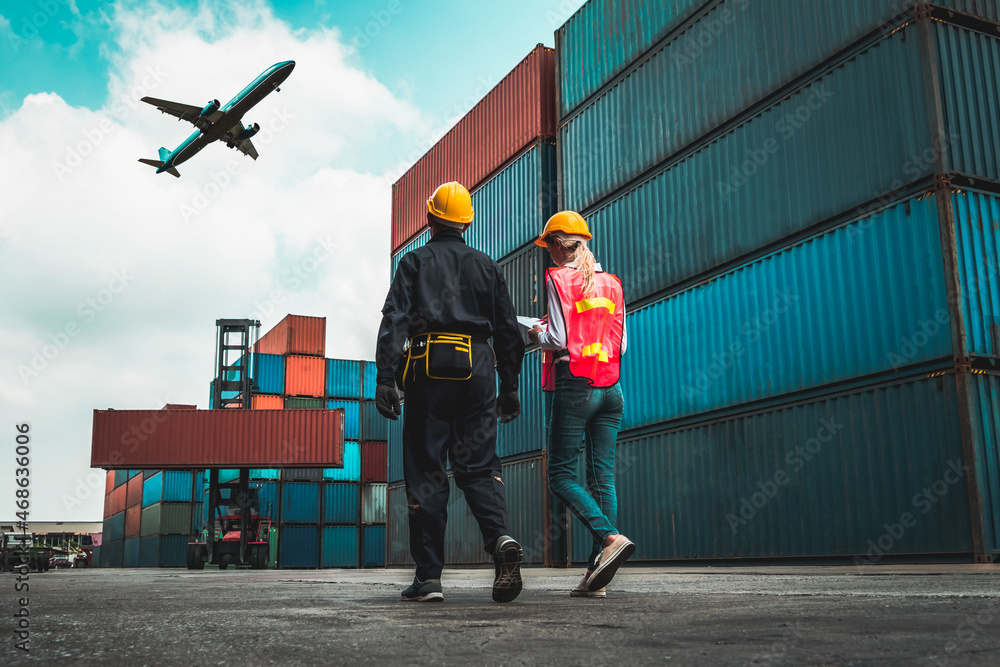 Industrial worker works with co-worker at overseas shipping container port . Logistics supply chain 