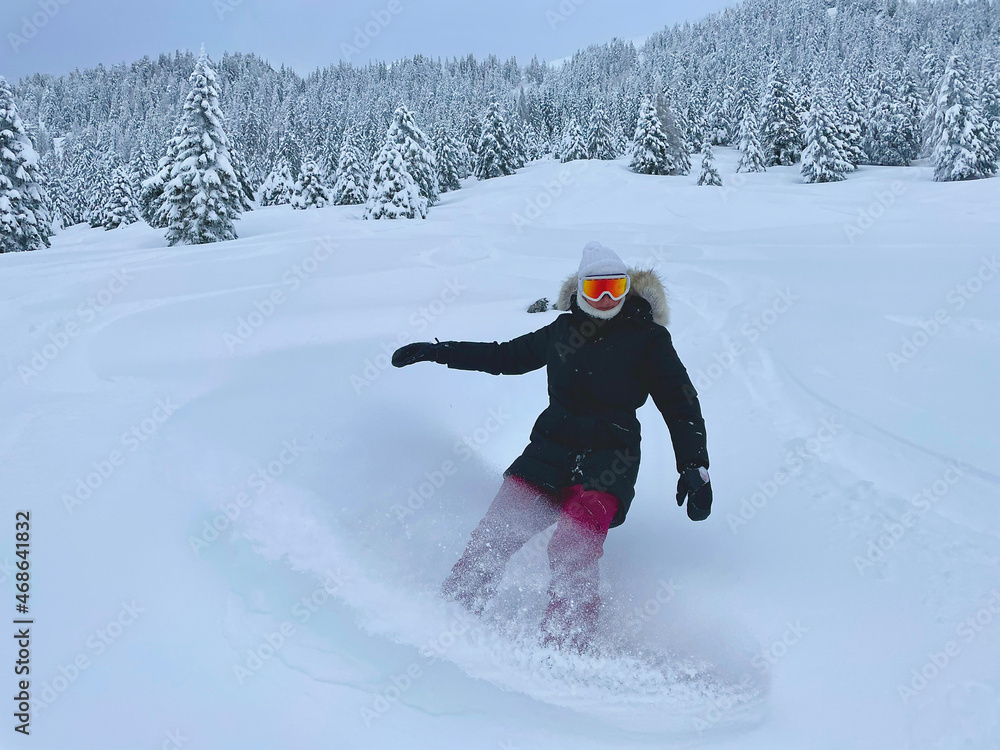 年轻的女单板滑雪运动员在野外撒下新鲜的粉末雪。