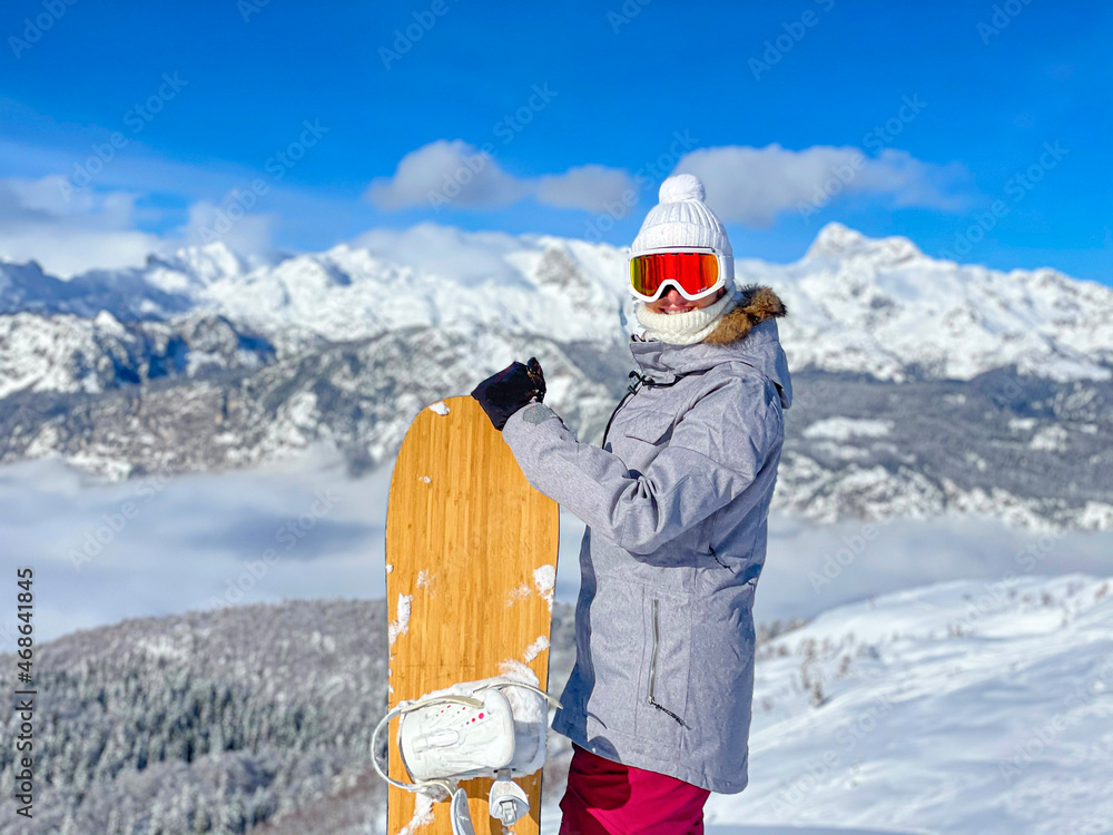 肖像：兴高采烈的女单板滑雪运动员在滑下滑雪道前对着镜头微笑