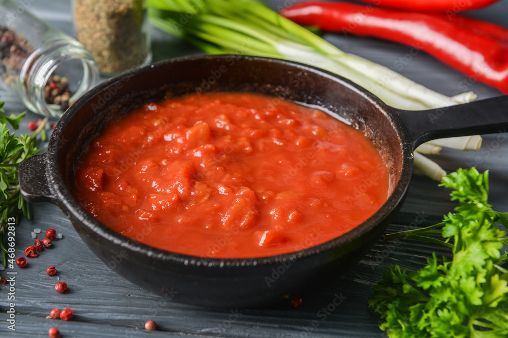 Frying pan with organic tomato sauce on dark wooden background