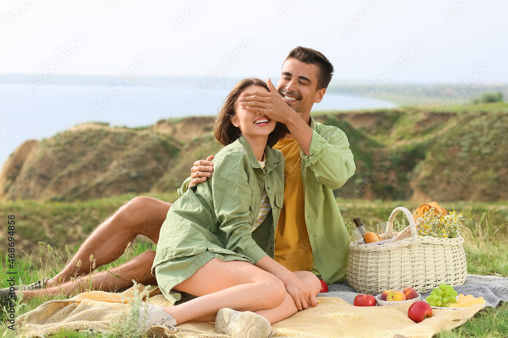 Happy young couple having romantic picnic in mountains