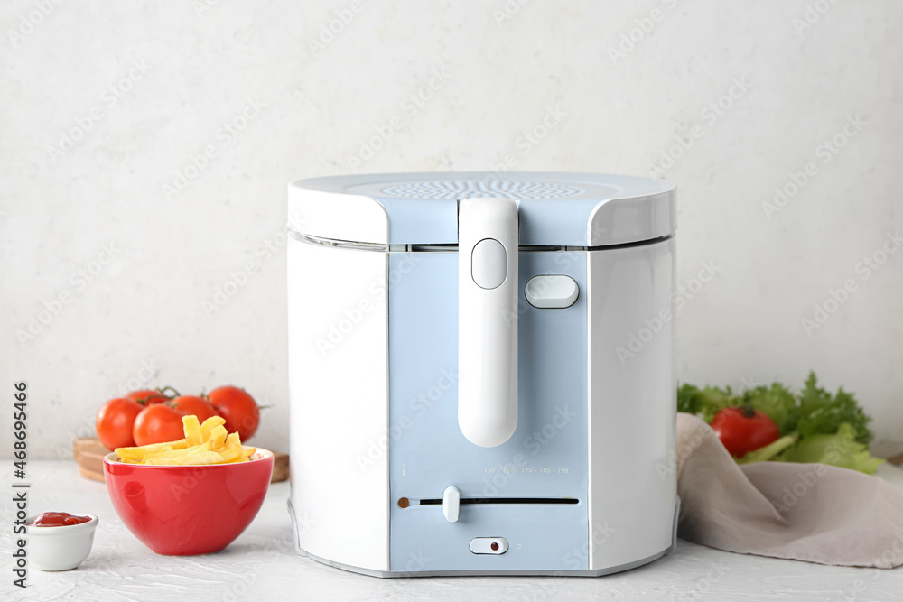 Deep fryer with bowl of fried potatoes and vegetables