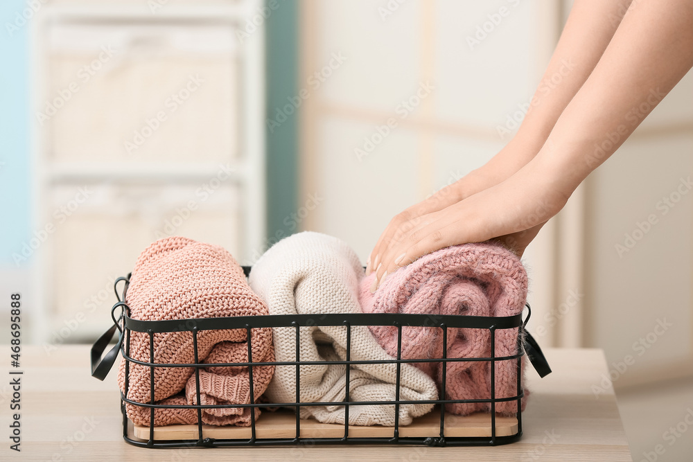 Woman putting clean clothes into basket on table, closeup