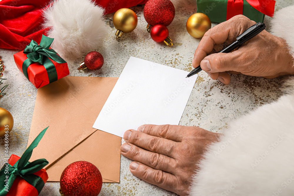 Santa Claus writing letter on light table with Christmas decor