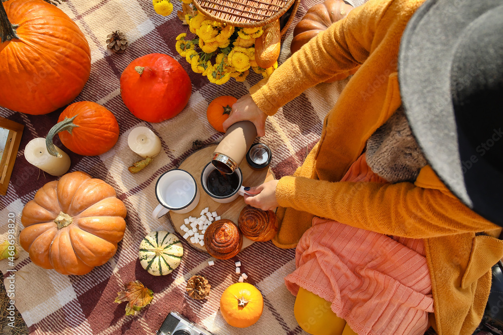 Young woman having romantic picnic on autumn day