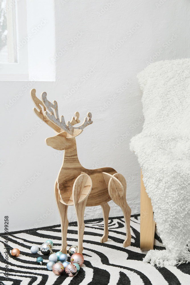 Wooden reindeer and Christmas balls near white wall