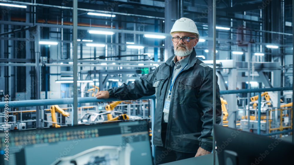 Car Factory: Confident Male Automotive Engineer Wearing Hard Hat, Looking at Camera. Technician Moni