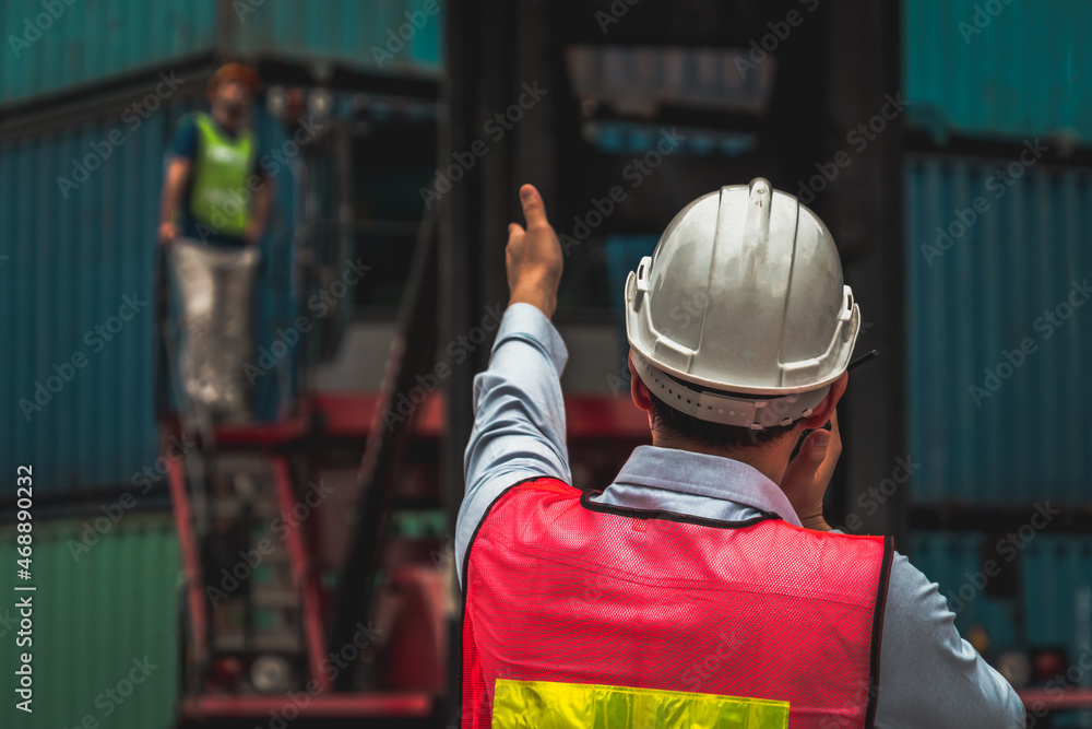 Industrial worker works with co-worker at overseas shipping container yard . Logistics supply chain 