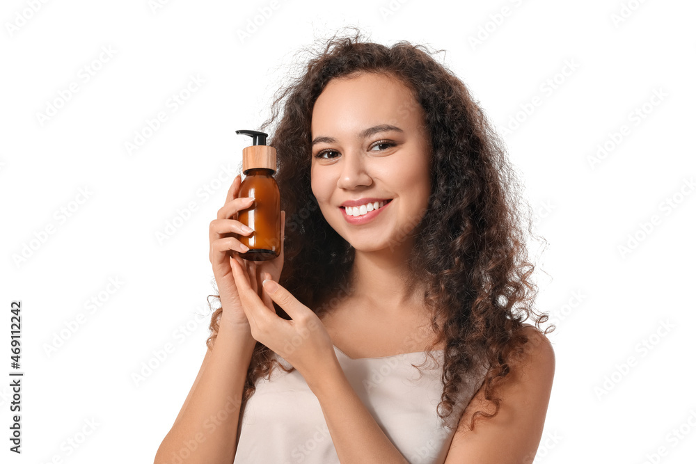 Beautiful African-American woman with cosmetic product in bottle on white background