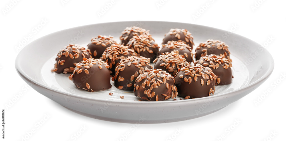 Plate with tasty flax seed candies on white background