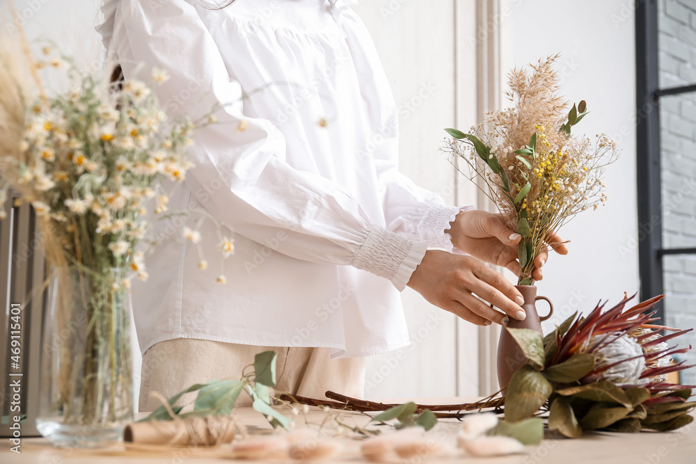 女花艺师在餐桌上用干花制作花束，特写