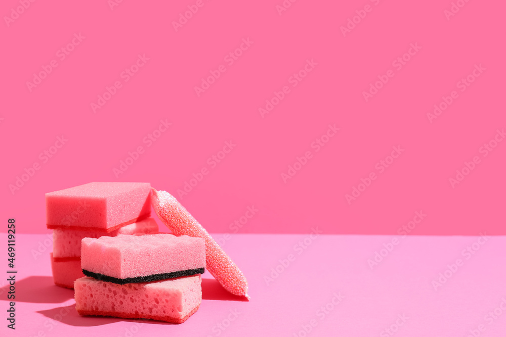 Pink cleaning sponges on color background