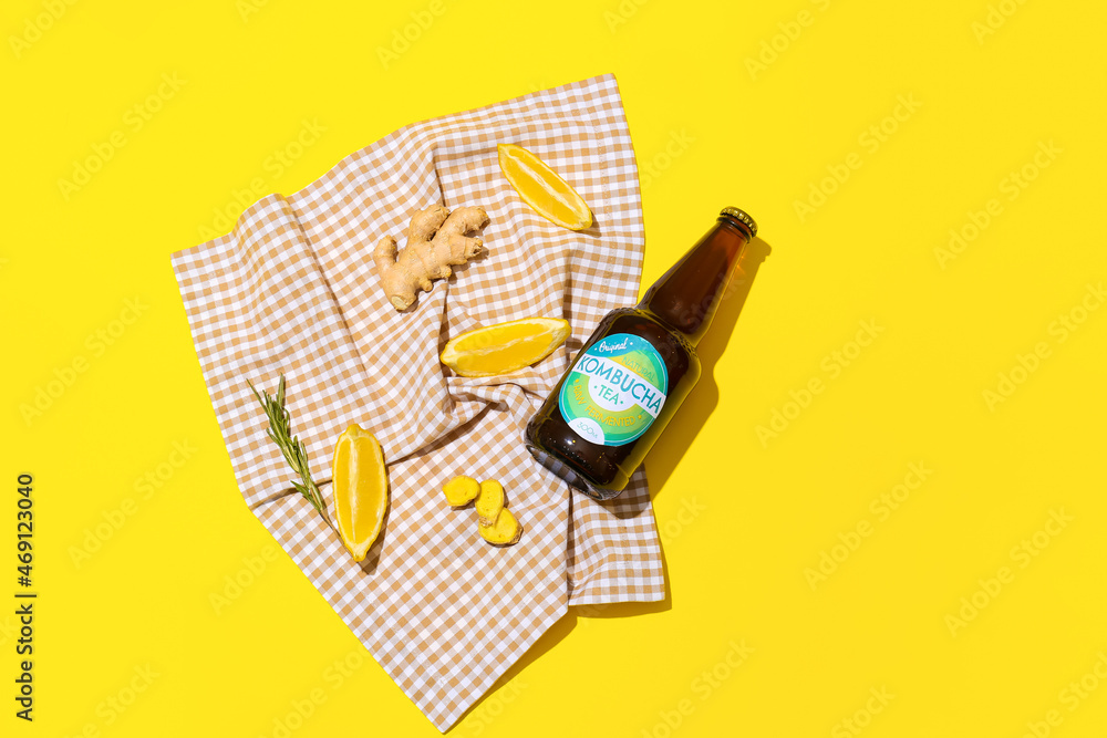 Bottle of natural kombucha with lemon and ginger on color background