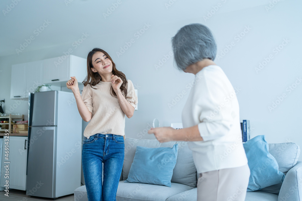 亚洲搞笑的老年妈妈和女儿在客厅里一起跳舞。