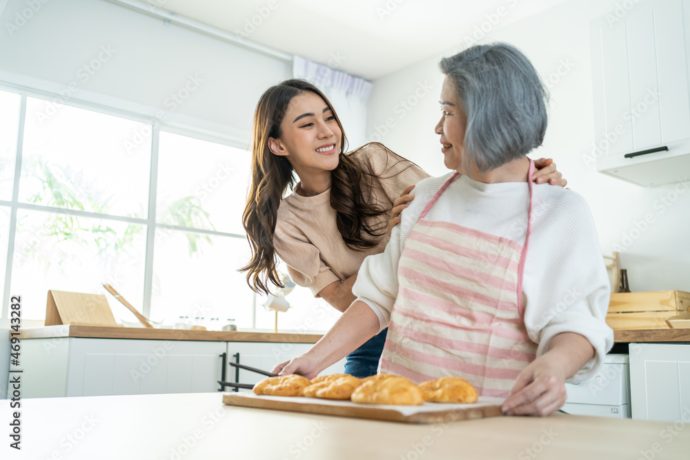 亚洲可爱的家庭，年幼的女儿看着年迈的母亲在厨房做饭。