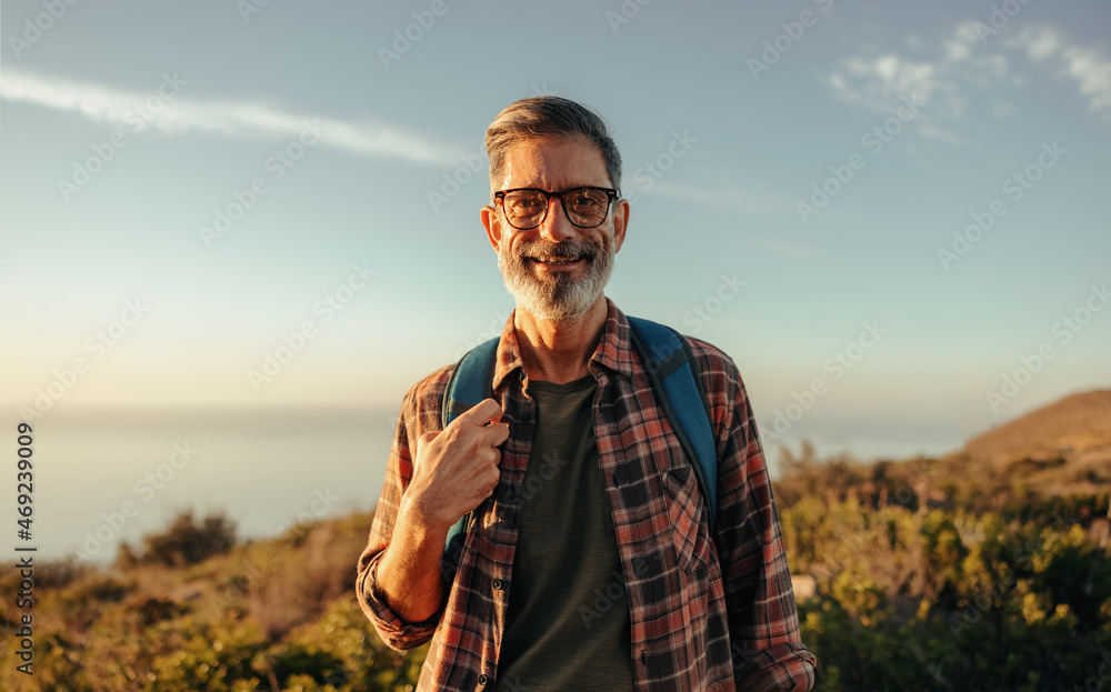 成熟的徒步旅行者站在户外对着镜头微笑