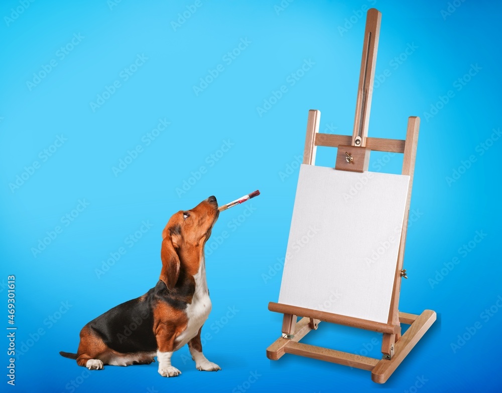 Dog artist. A pet sits near an easel with a white blank paper and holds a brush in its teeth.